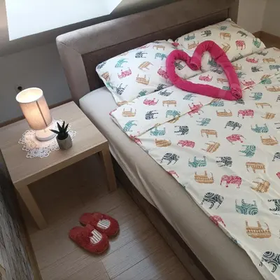a bed with a blanket with a pink ribbon on it at Apartman Vrnjacka zora in Vrnjačka Banja