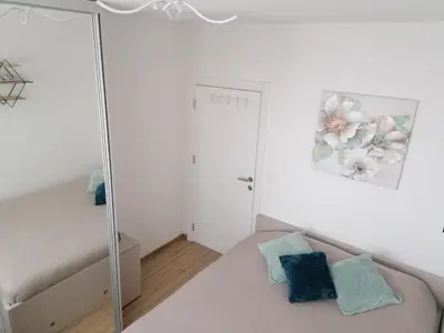 a white bedroom with a bed and a mirror at Ketigo Lux in Kopaonik