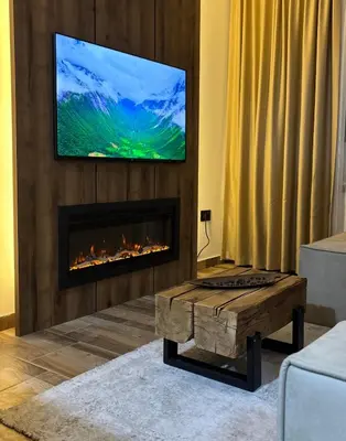 a living room with a fireplace with a tv above it at Apartman 16 Pancic in Kopaonik