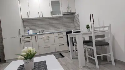 a kitchen with white cabinets and a table and a chair at Bili 2 in Paraćin