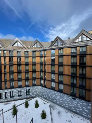an apartment building with snow on the ground at Woodside Kopaonik & SPA by Slopeview in Kopaonik