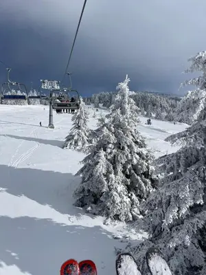 a pair of skiers on a ski lift in the snow at Woodside Kopaonik & SPA by Slopeview in Kopaonik