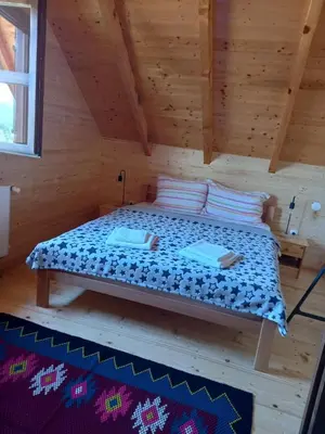a bed in a wooden room in a log cabin at Vikendice Karamarković in Goč