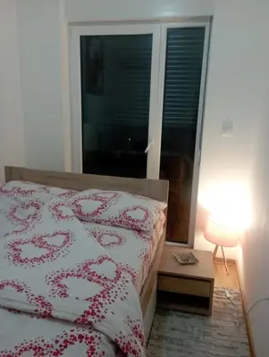 a bedroom with a bed with a red and white bedspread at Apartman Bajka in Vrnjačka Banja