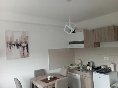 a kitchen with white appliances and a table in it at Apartman Bajka in Vrnjačka Banja
