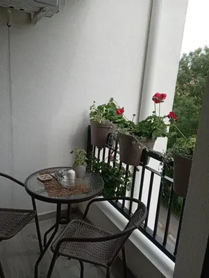 a balcony with a table and chairs and potted plants at Apartman Bajka in Vrnjačka Banja