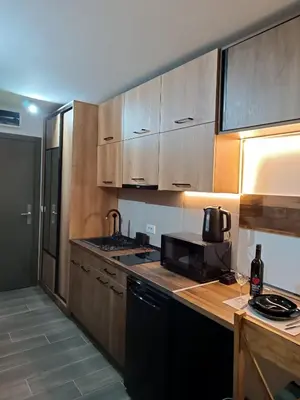 a kitchen with wooden cabinets and a black microwave at PETRA Apartman Kopaonik in Kopaonik