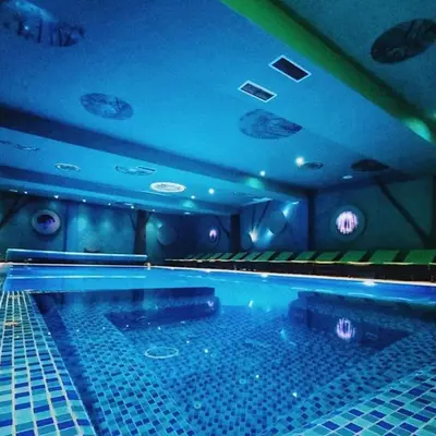 a large swimming pool in a room with blue lights at PETRA Apartman Kopaonik in Kopaonik