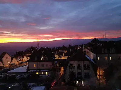 a view of a city at night with a sunset at PETRA Apartman Kopaonik in Kopaonik