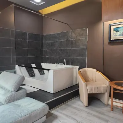 a bathroom with a bath tub and a chair at IN CLUB in Vrnjačka Banja