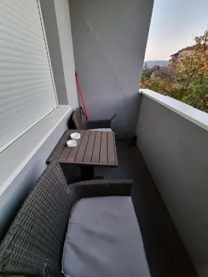 a small balcony with a wooden table and a window at Silver city 1 in Jagodina