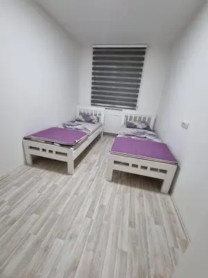 two beds in a room with white walls and wooden floors at Silver city 1 in Jagodina