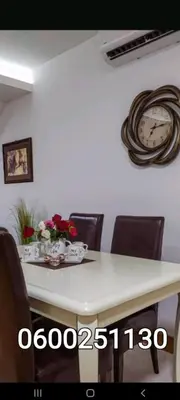 a dining room table with chairs and a clock on the wall at Silver city 1 in Jagodina
