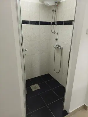 a bathroom with a shower with a black and white tiled floor at Apartman Aleksić u samom centru grada in Knjazevac.