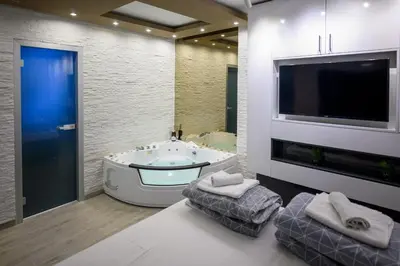 a bathroom with a tub and a tv and a tv at Apartman Nataly in Niš