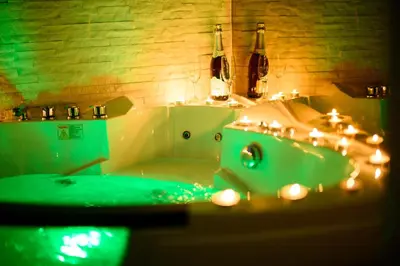 a bathroom with a tub and a sink with lights at Apartman Nataly in Niš