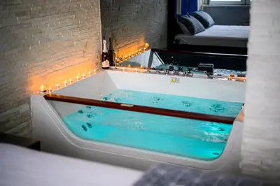 a bath tub with blue water in a room at Spa Apartman Grand in Niš