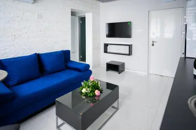 a living room with a blue couch and a table at Spa Apartman Grand in Niš