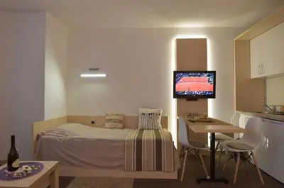 a bedroom with a bed and a table and a television at Konaci Kopaonik Lux Apartmani in Kopaonik