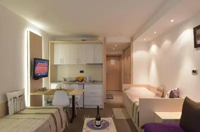 a bedroom with a bed and a desk and a kitchen at Konaci Kopaonik Lux Apartmani in Kopaonik