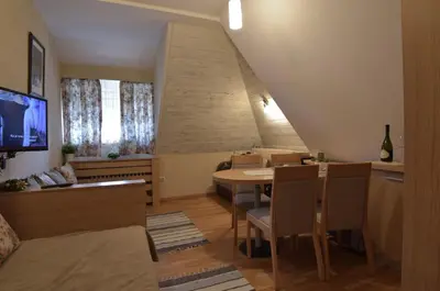 a dining room with a table and chairs and a tv at Konaci Kopaonik Lux Apartmani in Kopaonik