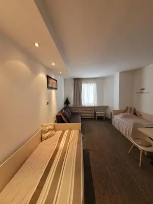 a hotel room with two beds and a couch at Konaci Kopaonik Lux Apartmani in Kopaonik