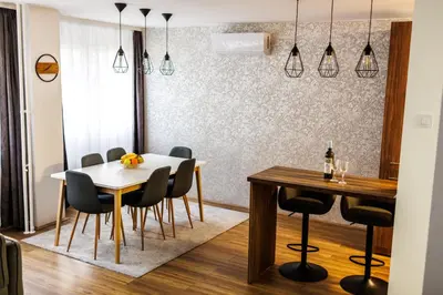 a dining room with a white table and chairs at A Comfortable Base for Work & Life in Niš