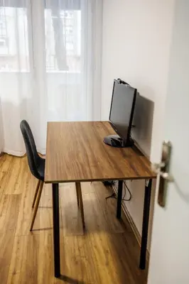 a wooden table with a computer monitor and a chair at A Comfortable Base for Work & Life in Niš