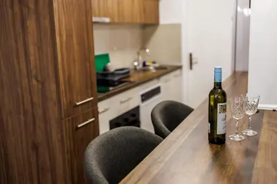 a bottle of wine sitting on a wooden table with chairs at A Comfortable Base for Work & Life in Niš