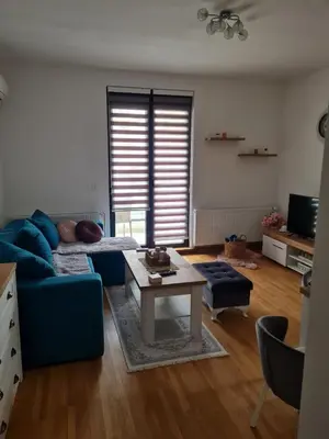 a living room with a blue couch and a table at Apartman Tina in Vrnjačka Banja
