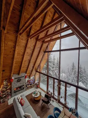 a living room with a christmas tree and a large window at Sofia - Mountain Home in Kopaonik