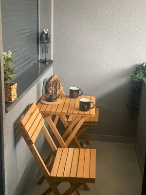a wooden table and benches on a balcony at SpaNish apartman in Niš
