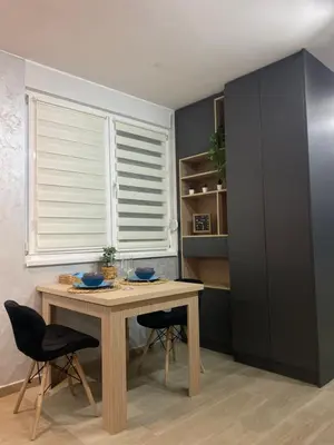 a dining room with a table and chairs and a window at SpaNish apartman in Niš