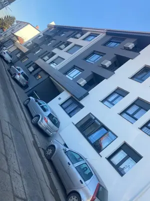 two cars parked in front of a building at SpaNish apartman in Niš