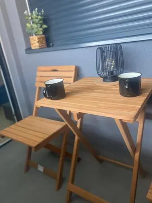 a wooden table and chair with two cups on it at SpaNish apartman in Niš