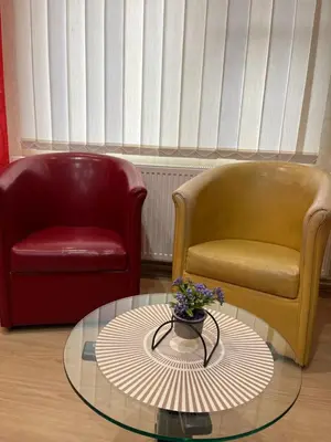 two chairs and a glass table with a vase of flowers on it at Apartmani Tomašević in Paraćin