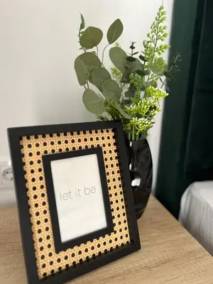 a picture frame on a table with a vase of flowers at Magija in Vrnjačka Banja