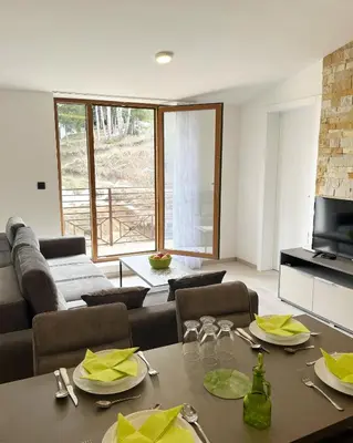 a living room with a table and a couch at Sunrise Apartman Kopaonik in Cajetina