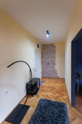 a living room with a table and a stone wall at Fenix1 in Knjazevac.