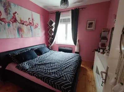 a bedroom with a black bed with pink walls at Nirvana apartment in Niš