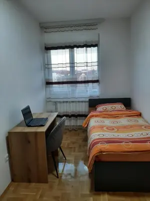 a bedroom with two beds and a desk with a laptop at Apartman Milic Pirot-Zapadni Kej 10 in Pirot