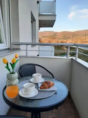 a table with a croissant and two cups and a table on a balcony at Apartman Milic Pirot-Zapadni Kej 10 in Pirot