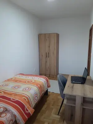 a bedroom with a bed and a desk with a laptop at Apartman Milic Pirot-Zapadni Kej 10 in Pirot