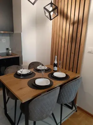 a wooden table with chairs and wine glasses on it at Apartman Milic Pirot-Zapadni Kej 10 in Pirot