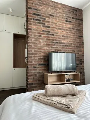 a bedroom with a brick wall and a television at DREAM apartments in Niš