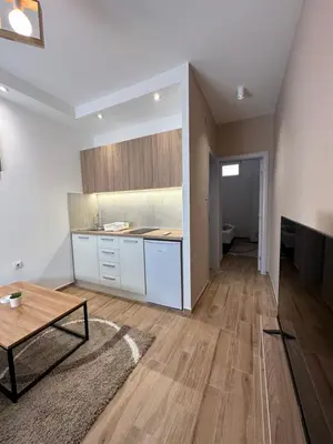 a kitchen with white cabinets and a table in a room at DREAM apartments in Niš