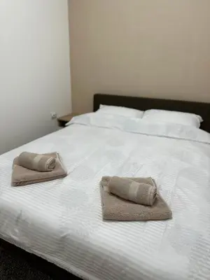 a white bed with two towels on top of it at DREAM apartments in Niš