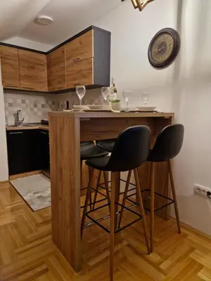 a kitchen with a bar with two chairs and a clock at Apartman Bošković Vrnjačka Banja in Vrnjačka Banja