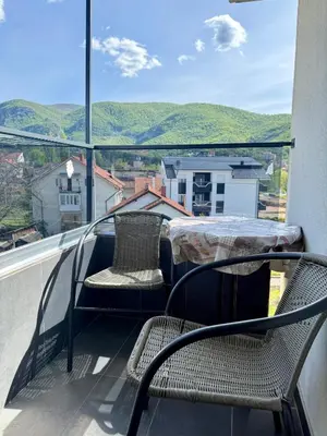 a balcony with a table and chairs and a view of mountains at Aleksandar apartman Sokobanja in Soko Banja