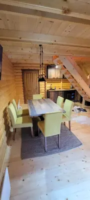a dining room with a wooden table and chairs at Apartmani Prica in Crni Vrh